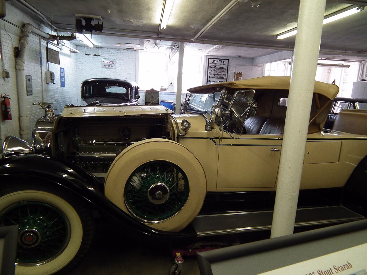 A cream-colored classic touring car with white-wall tires on display inside the Larz Anderson Auto Museum