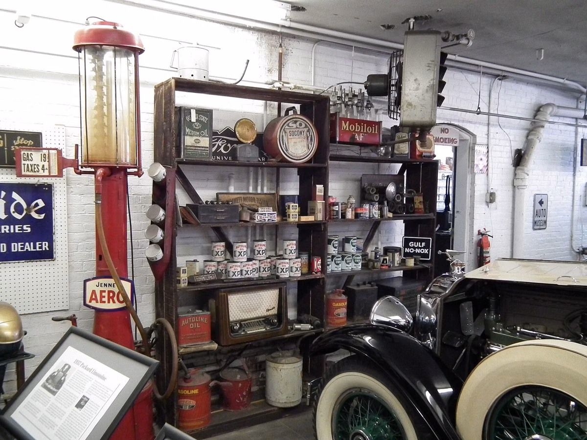 A recreated vintage service station inside the Larz Anderson Auto Museum, with old gas pumps, oil cans and enamel signs