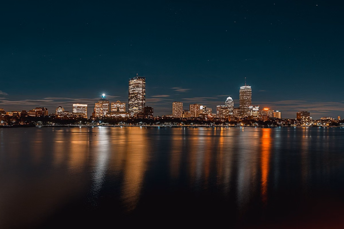 A city skyline lit up at night, reflected in the water