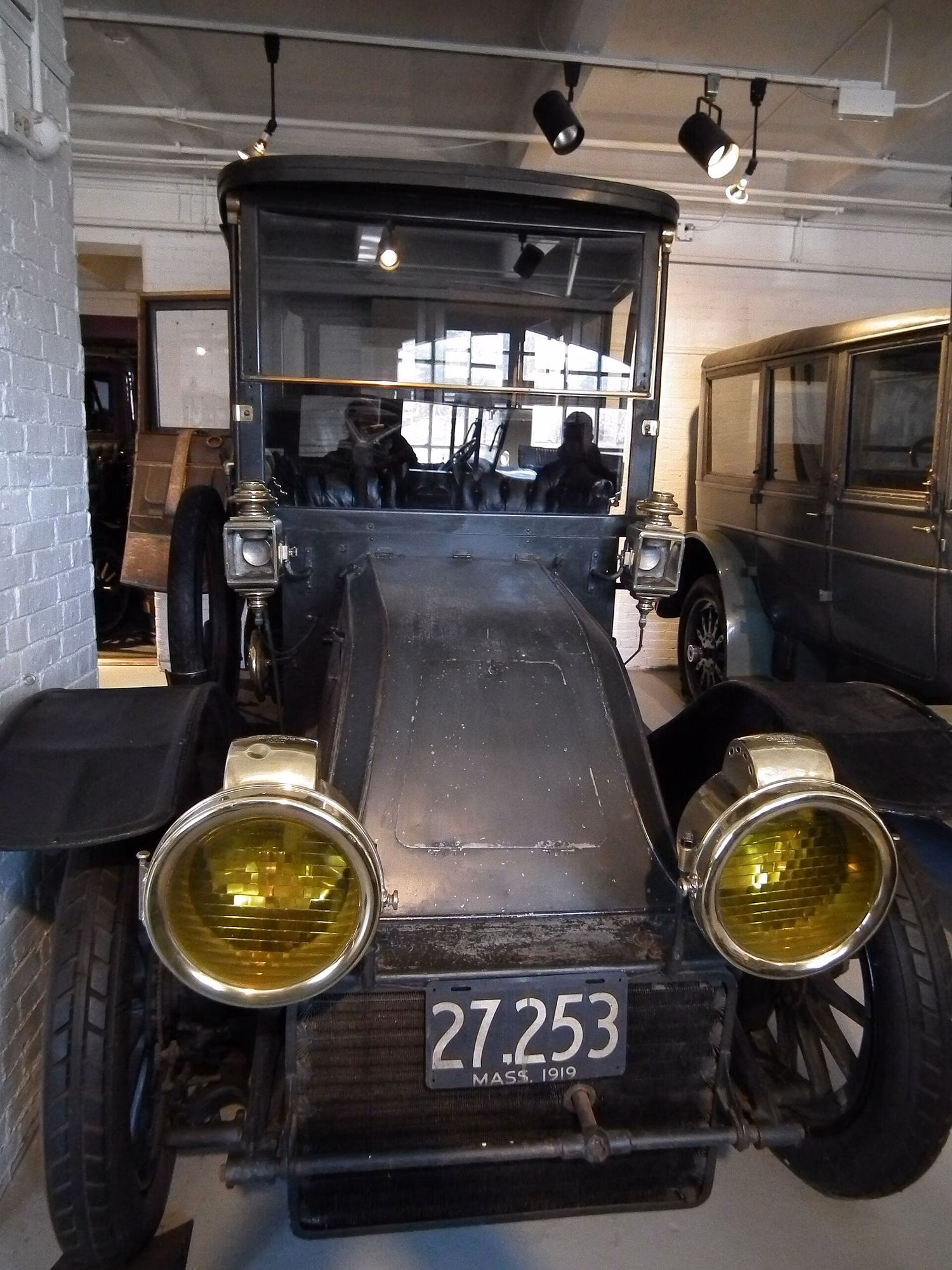 An early motorcar with brass lamps on display in the Larz Anderson Auto Museum