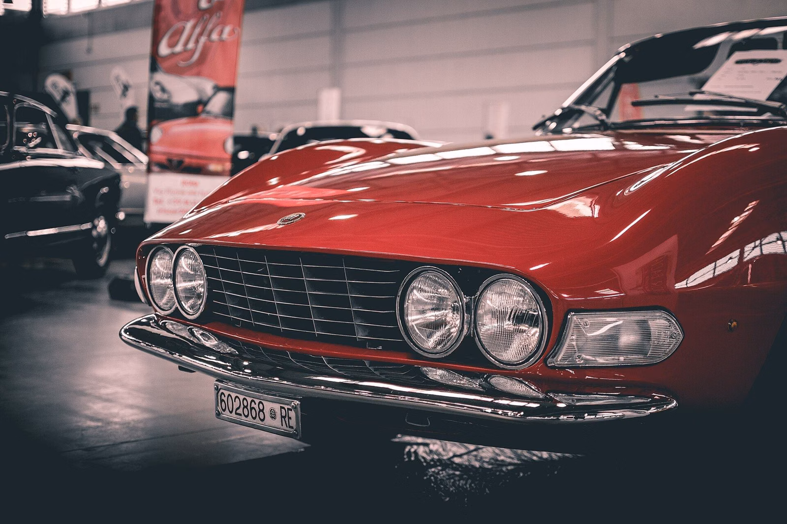 A red classic sports car parked in a row at an outdoor classic car show