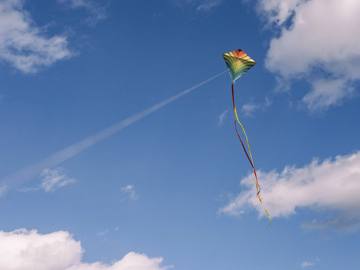 A colorful kite flying against a blue sky with white clouds